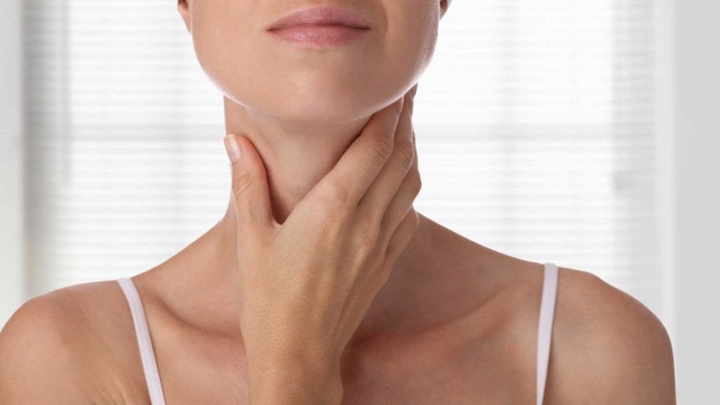 Woman gently touching her neck, illustrating Thyroid & Hypothyroidism health concerns.