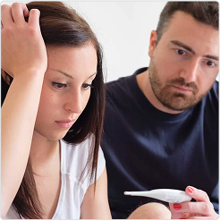 Couple sitting together, one holding a pregnancy test, both appearing concerned, representing infertility.