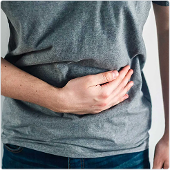 Person holding their abdomen with one hand, indicating abdominal discomfort.
